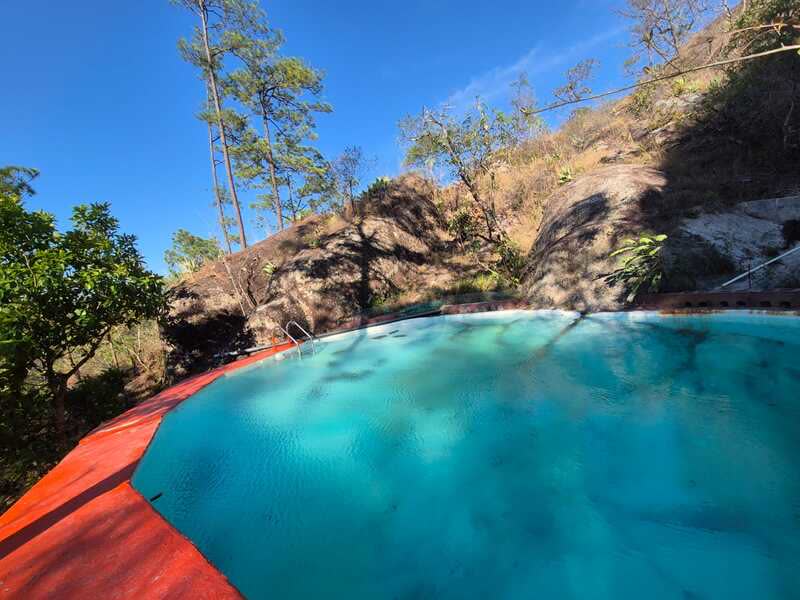 Piscina rodeada de rocas y pinos